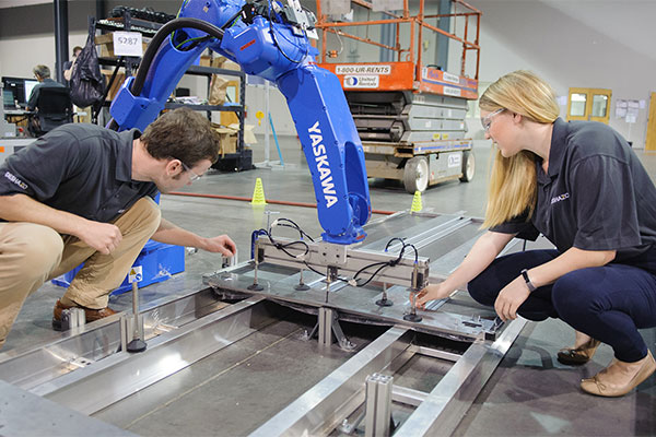 Two manufacturing students working with a robot arm