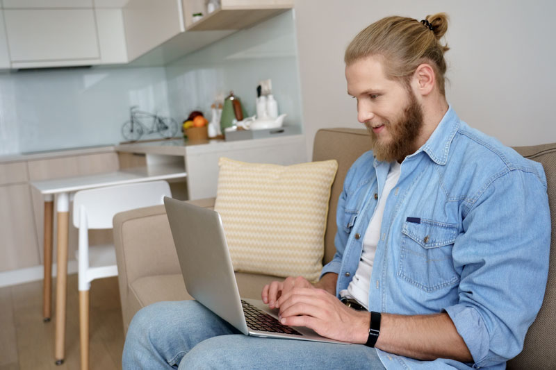 Male sitting on a couch using a laptop