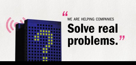 A graphic image of a building with the windows lit up in a "?" pattern to symbolize the more recently prevalent issue of facility capacity usage and how we monitor it. The graphic includes the quote "We are helping companies solve real problems."