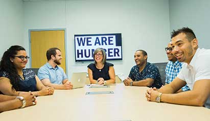 Group of people sitting in front of a we are humber sign
