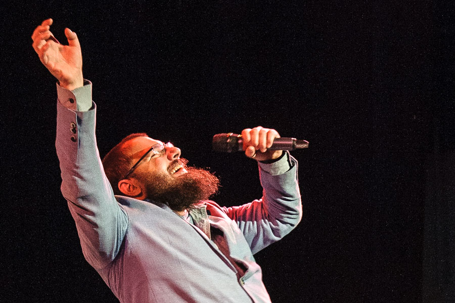 Bearded man singing into a microphone