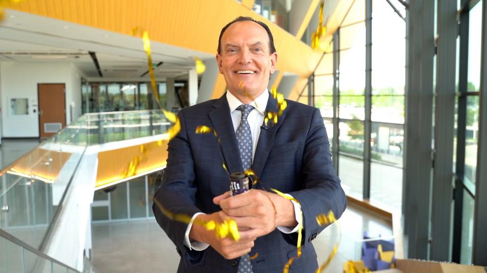 Humber College President and CEO Chris Whitaker smiles as streamers shoot out of a party favour in his hand at the Barrett CTI