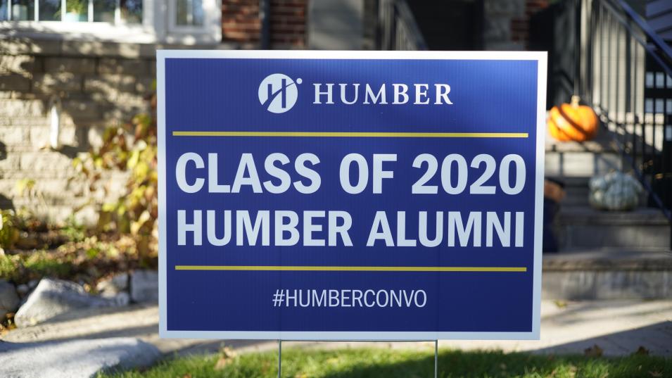 The words "Class of 2020 Humber Alumni" are printed in white on a blue sign with the Humber logo