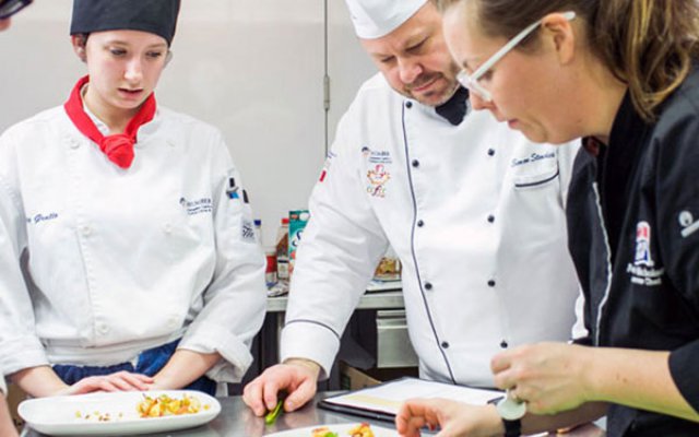 three people working in the culinary lab arranging plates of food